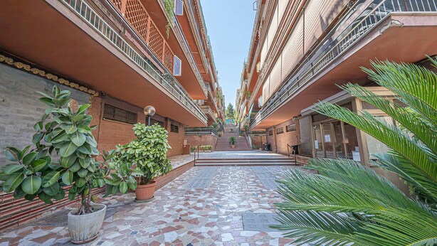 Um pátio com piso de azulejos, plantas em vasos e uma escadaria que dá acesso aos andares superiores.