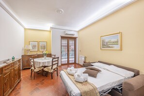 Ein Hotelzimmer mit Bett, Tisch mit Stühlen, Schreibtisch und einem Bild an der Wand.