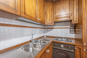 Eine Küche mit Holzausstattung, einer Edelstahl-Spüle und einem Gasherd.