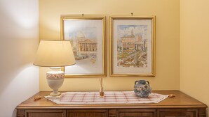 Uma mesa com uma luminária, um vaso e duas obras de arte emolduradas.