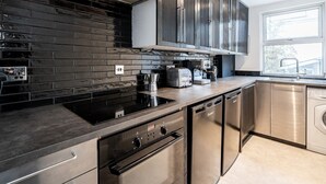 Cozinha moderna com eletrodomésticos de aço inoxidável, painel de azulejos pretos e janela que oferece luz natural.