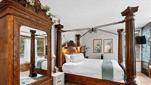 A four-poster bed with a wooden frame and white bedding, a large mirror, and a small bedside table with a lamp. - Wildwood Canyon Inn Silver Meadows Room (Telluride)