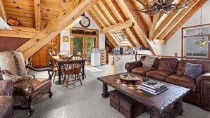 Una camera mansardata accogliente con travi in legno, un'area pranzo e un divano in pelle.