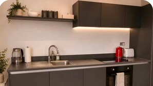 A modern kitchen with a built-in oven, a sink, and a coffee maker. - Salford Serenity - Modern 2 Bedroom Apartment (Salford)