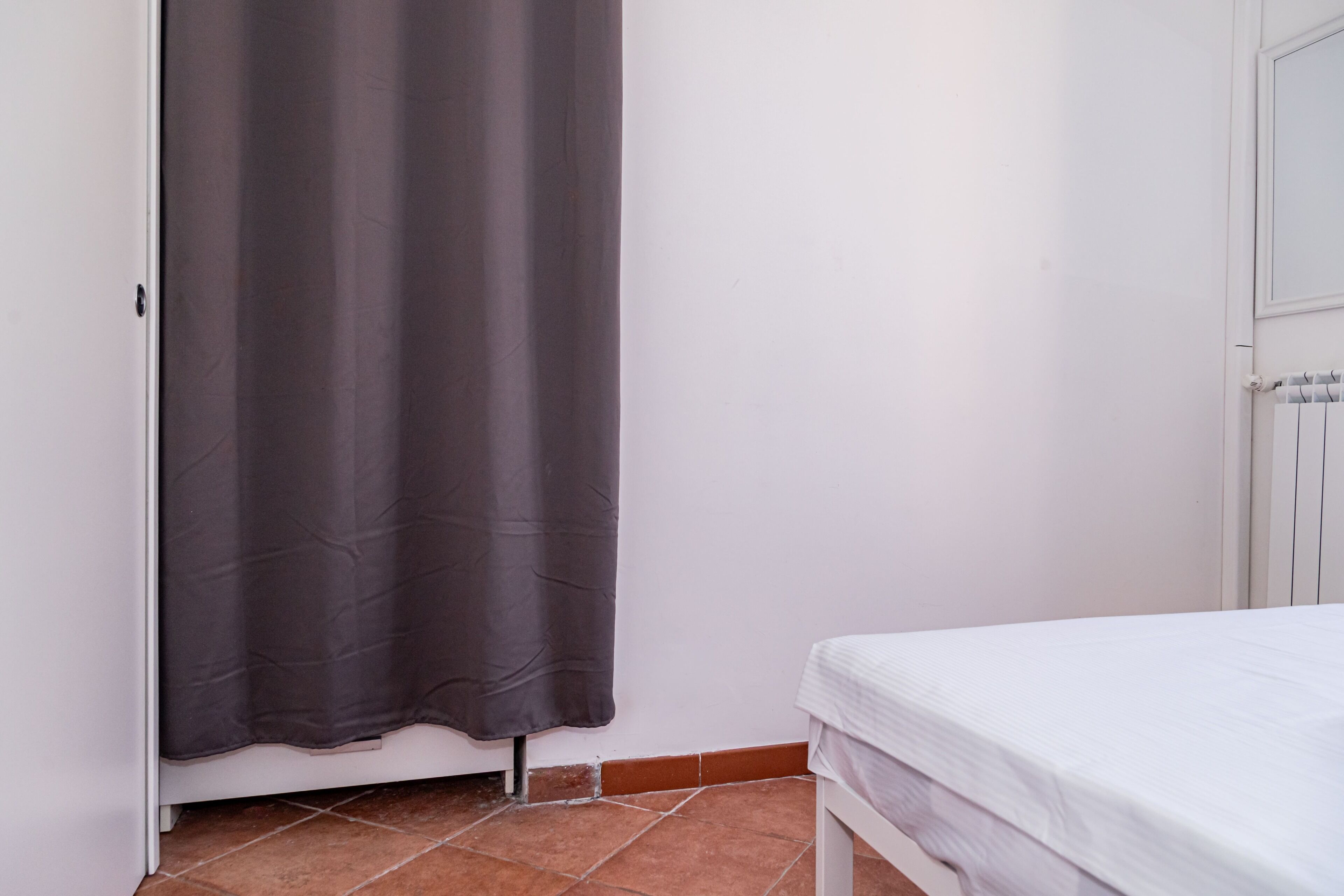 A bedroom with a bed, a door, and a curtain.