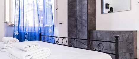 Una habitación de hotel con cama, armario, espejo y ventana con cortinas.