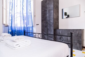 A hotel room with a bed, a wardrobe, a mirror, and a window with curtains. - Aurelia Vatican Home (Roma)