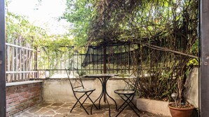 A patio with stone flooring, two metal chairs, a small round table, and a potted plant. - Aurelia Vatican Home (Roma)