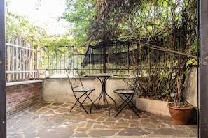 A patio with stone flooring, two metal chairs, a small round table, and a potted plant. - Aurelia Vatican Home (Roma)