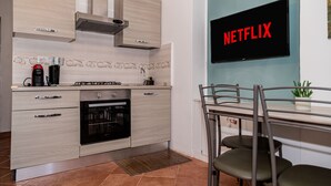 A modern kitchen with a built-in oven, a coffee maker, and a wall-mounted television displaying 'NETFLIX'. - Aurelia Vatican Home (Roma)