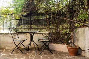 An outdoor seating area with two metal tables and chairs, surrounded by a stone floor and a concrete wall. - Aurelia Vatican Home (Roma)