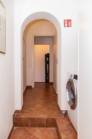 A hallway with a washing machine, a fire alarm, and a staircase leading to another room. - Aurelia Vatican Home (Roma)