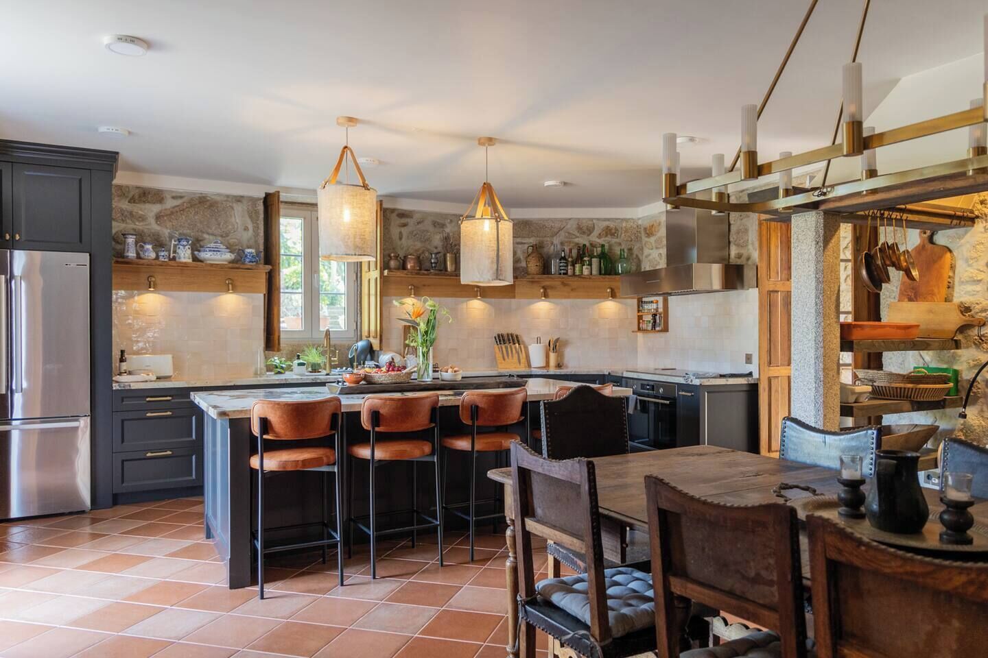 Une cuisine moderne dotée d’un îlot central, de tabourets de bar et de luminaires suspendus.