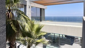 Een modern balkon met glazen hekwerk, met uitzicht op de zee.