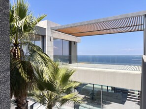 Ein moderner Balkon mit Glasgeländer und Meerblick.