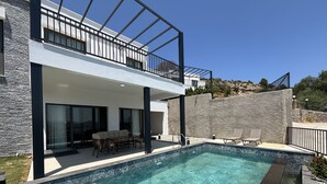 Una moderna casa a due piani con piscina, mobili da esterno e un muro in pietra.