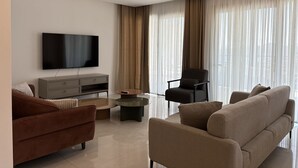 Un soggiorno moderno con una TV a schermo piatto, un divano, una poltrona e un tavolino.