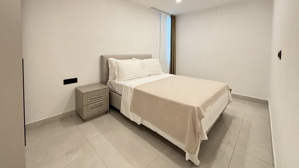Una camera da letto con un letto, un comodino e una finestra con tende.