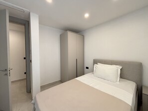 Ein Schlafzimmer mit einem Bett, einem Kleiderschrank und einer Tür zu einem anderen Raum.