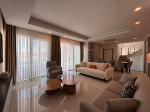 A modern living room with a sofa, two coffee tables, and a dining area with chairs.