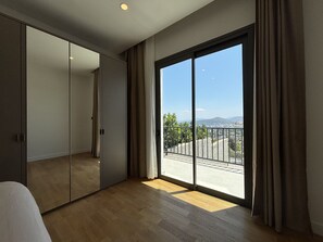 A room with a large sliding door leading to a balcony with a city view. - Private Pool Villa for Groups | Türkbükü (Bodrum)