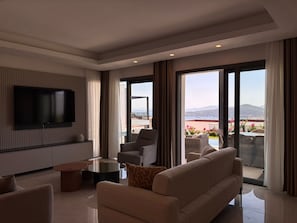 A modern living room with a flat-screen TV, comfortable seating, and a balcony with a view. - Private Pool Villa for Groups | Türkbükü (Bodrum)