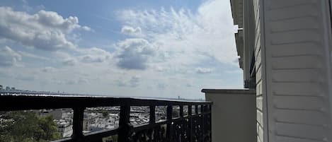 A balcony with a view of a cityscape, a clear sky, and the sun shining.