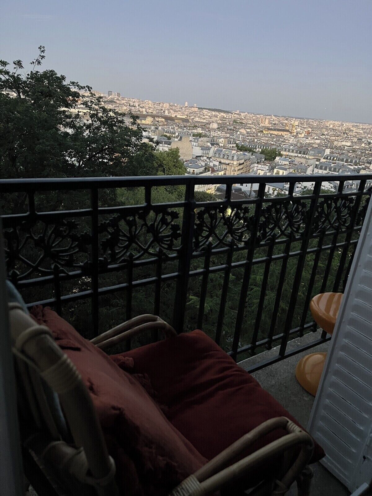 Ein Balkon mit Blick auf eine Stadtlandschaft, ein Stuhl und ein kleiner Tisch.