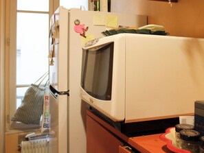 Eine Küche mit einem weißen Kühlschrank, einer Mikrowelle und einem Fenster.