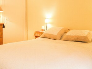 Ein Hotelzimmer mit einem Bett, einem Nachttisch, einer Lampe und einer Tür.