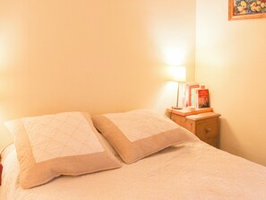 Ein Bett mit zwei Kissen und einem Nachttisch mit Lampe und Büchern.