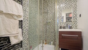A bathroom with a glass-enclosed shower, a white sink, and a mirror above the sink. - Charming Well Purified Studio Near Sacre Coeur (Paris)