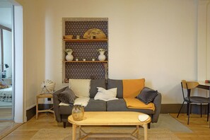 A living room with a sofa, a coffee table, a bookshelf, and a chair. - Charming Well Purified Studio Near Sacre Coeur (Paris)