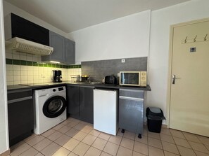 A compact kitchen with a washing machine, a microwave, and a small refrigerator. - Ground floor apart, walking distance to the beach (Cabourg)