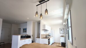 A modern kitchen with a wooden dining table, white cabinets, and pendant lighting. - Sea view apartment, Sanguinaires Islands terraces (Ajaccio)