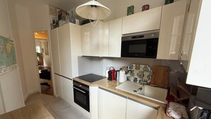 Eine kleine Küche mit weißen Schränken, einem schwarzen Backofen, einer Edelstahl-Mikrowelle und einer Holz Arbeitsplatte.