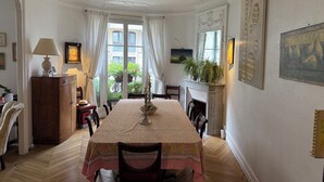 Ein Esszimmer mit Tisch für vier Personen, einem Kamin und Blick durch große Fenster ins Freie.