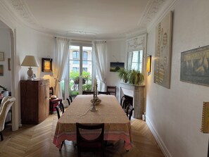 A dining room with a table set for four, a fireplace, and a view of the outside through large windows. - Large, quiet apartment with balcony in Paris 12 (Paris)