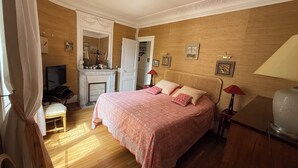 Ein Schlafzimmer mit Bett, Fernseher, Schreibtisch und Spiegel.