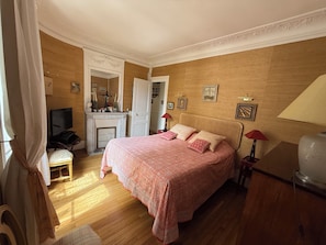 A bedroom with a bed, a television, a desk, and a mirror. - Large, quiet apartment with balcony in Paris 12 (Paris)