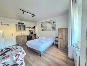 A compact room with a bed, a kitchenette, and a window. - Studio with terrace and barbecue, close to the sea (Grandcamp-Maisy)