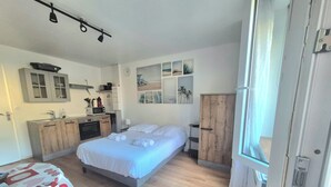 Een slaapkamer met een bed, een kledingkast, een bureau en een kitchenette.