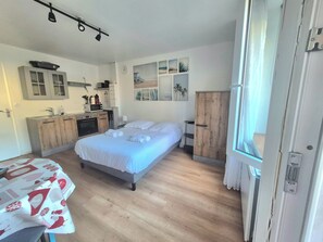 Ein Schlafzimmer mit Bett, Kleiderschrank, Schreibtisch und einer Küchenzeile.