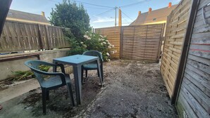 Een achtertuin met een tafel en stoelen, een houten omheining en een boom.