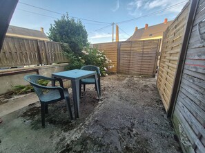 Ein Garten mit Tisch und Stühlen, einem Holzzaun und einem Baum.