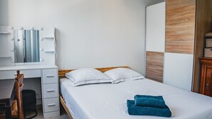 Et soveværelse med seng, træsenggavl, skrivebord med spejl og garderobeskab.
