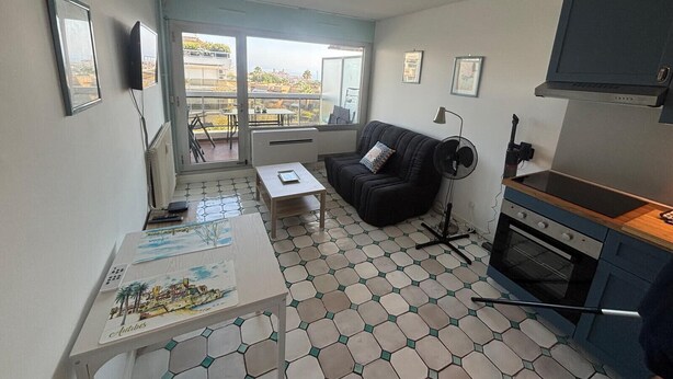 Un espacio habitable compacto con kitchenette, comedor y balcón con vistas a la ciudad.