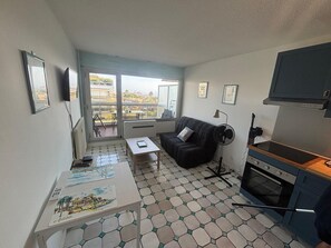 Ein kompakter Wohnbereich mit Küchenzeile, Essplatz und Balkon mit Blick auf die Stadt.
