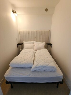 A single bed with a headboard, two bedside tables, and a wall-mounted light fixture. - Apartment with sea view, terrace and swimming pool (Antibes)