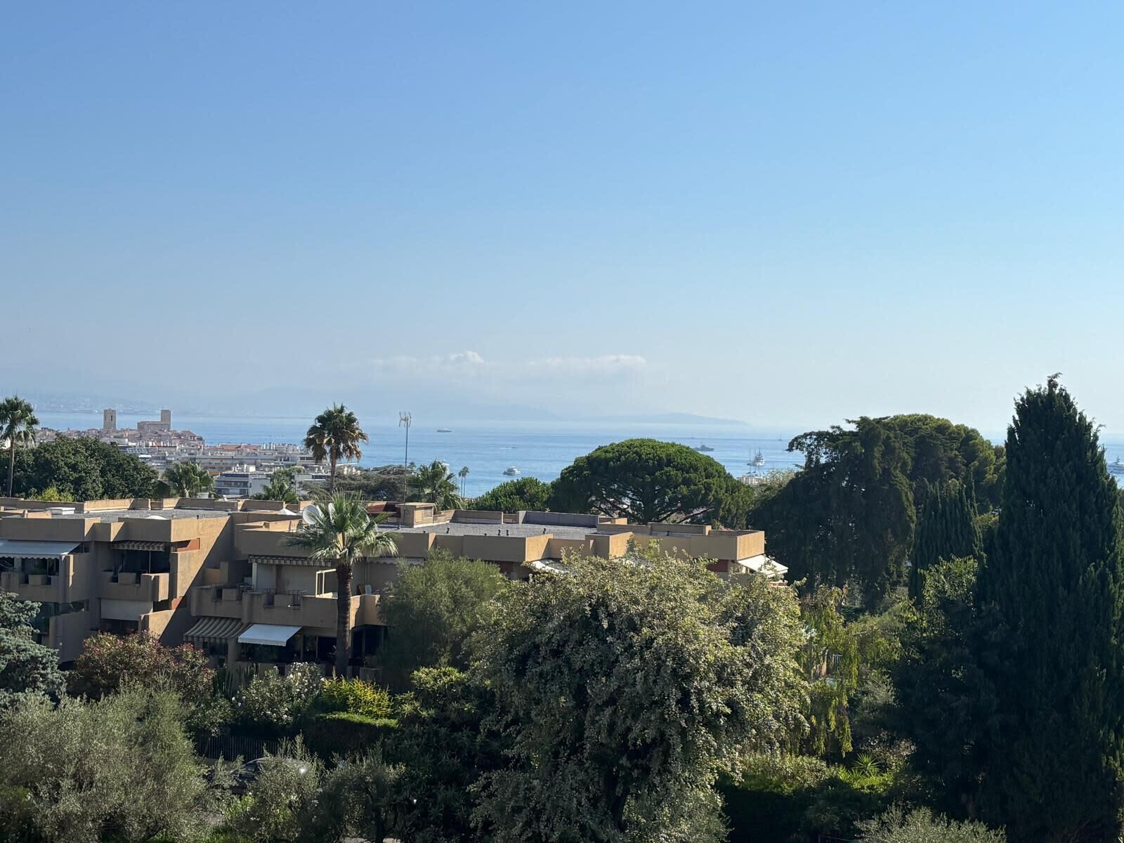 Eine Küstenstadt mit Gebäuden, Bäumen und freiem Blick auf das Meer.